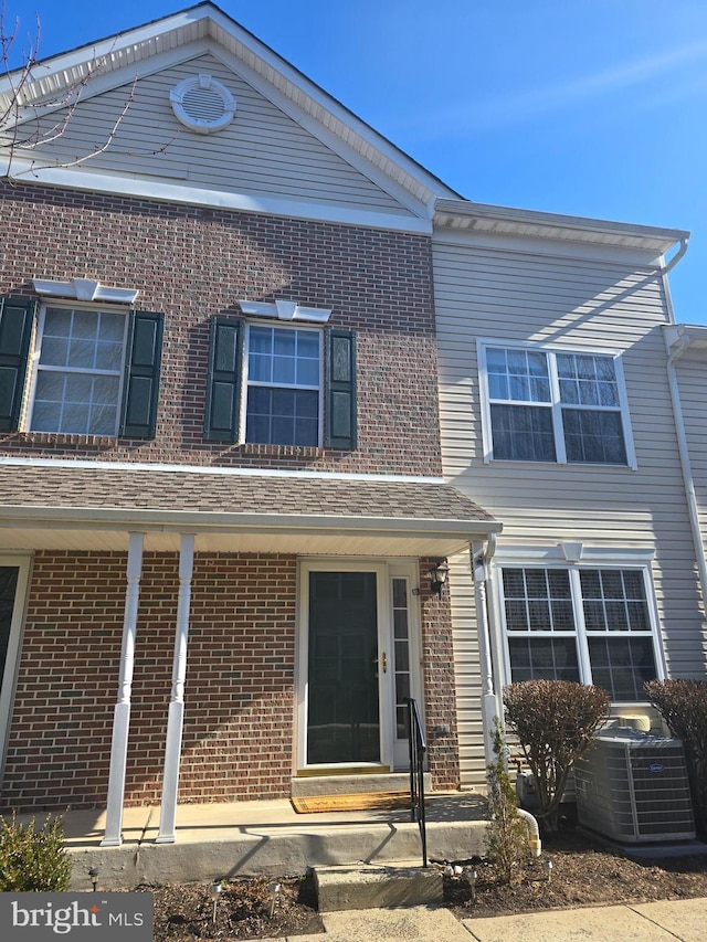 view of front facade featuring central AC unit and brick siding