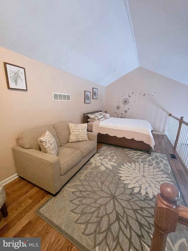 bedroom featuring vaulted ceiling, visible vents, baseboards, and wood finished floors