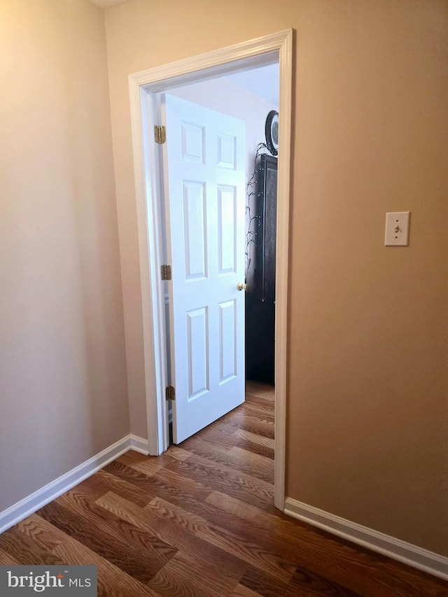 hallway featuring baseboards and dark wood-style flooring