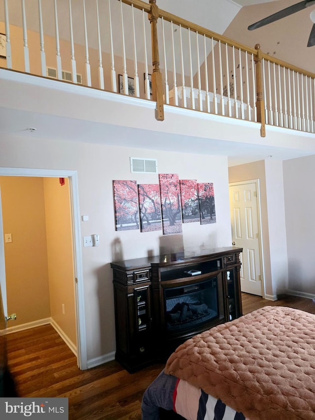 bedroom featuring visible vents, baseboards, a high ceiling, and dark wood-style floors