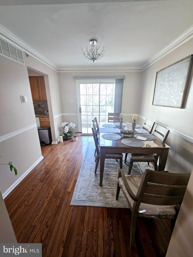 dining room featuring visible vents, ornamental molding, baseboards, and wood finished floors