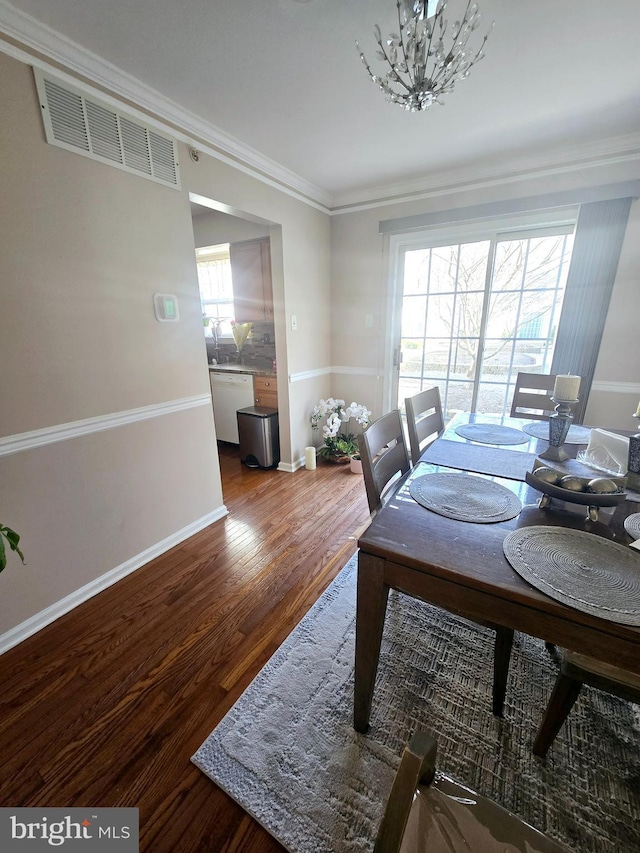 dining area with crown molding, wood finished floors, visible vents, and baseboards