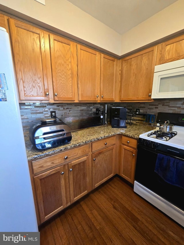 kitchen featuring dark wood-style floors, stone counters, backsplash, and white appliances