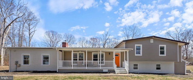 split level home with a porch, stucco siding, and a chimney