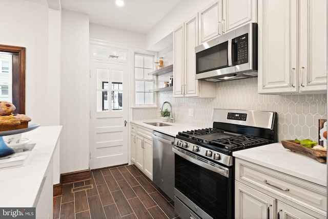 kitchen featuring a sink, open shelves, tasteful backsplash, stainless steel appliances, and light countertops