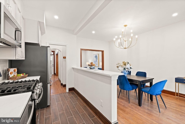 kitchen featuring a peninsula, dark wood-type flooring, white cabinets, light countertops, and appliances with stainless steel finishes