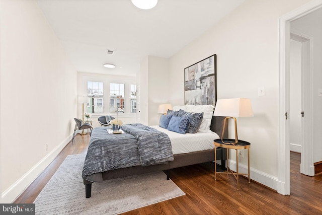 bedroom with visible vents, baseboards, and wood finished floors