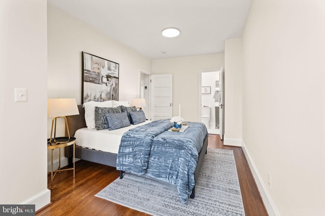 bedroom with ensuite bathroom, baseboards, and wood finished floors