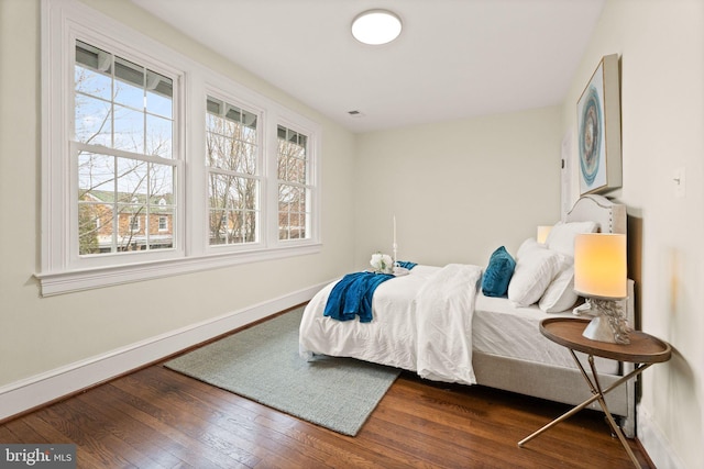 bedroom with hardwood / wood-style flooring, multiple windows, visible vents, and baseboards