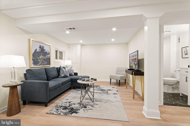 living room featuring visible vents, baseboards, light wood-style flooring, and decorative columns