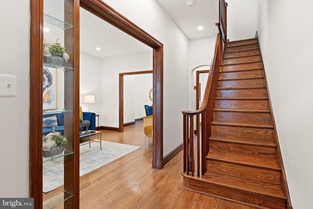 stairway featuring recessed lighting, wood finished floors, and baseboards