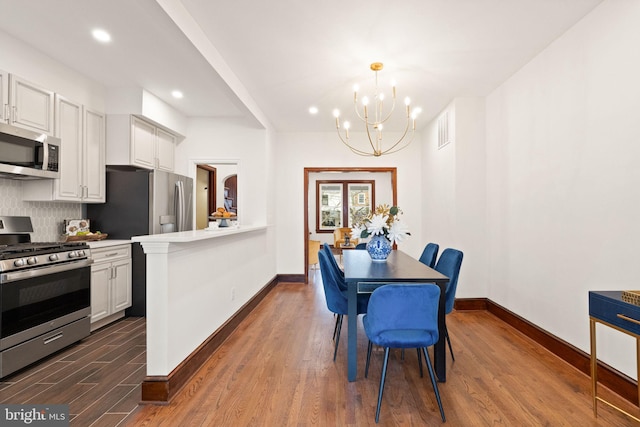 dining space with dark wood finished floors, a notable chandelier, recessed lighting, and baseboards