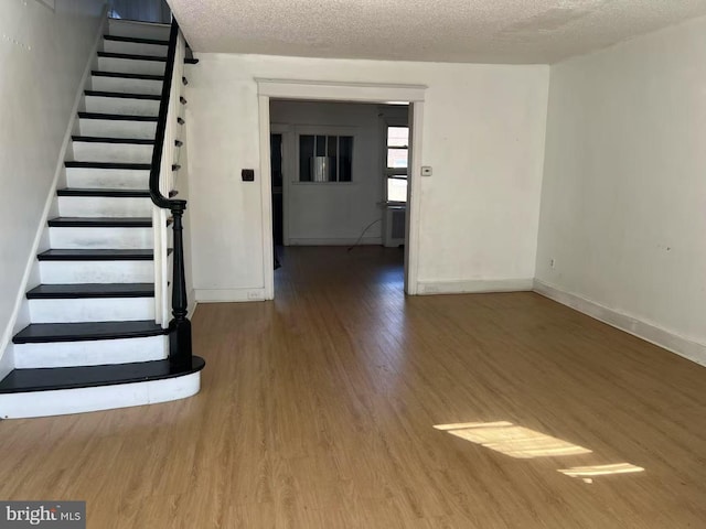 interior space featuring stairs, wood finished floors, baseboards, and a textured ceiling