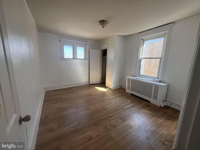 unfurnished bedroom with radiator, baseboards, and wood finished floors