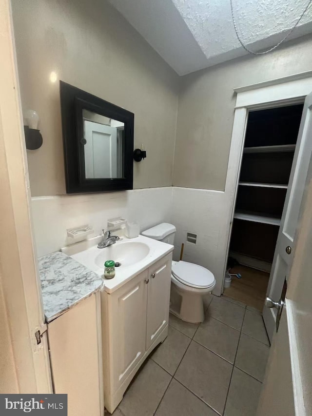 bathroom with toilet, vanity, and tile patterned flooring