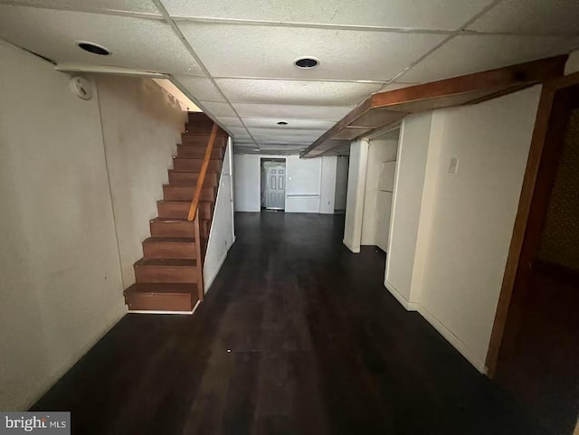 hall with a drop ceiling, dark wood-style flooring, and stairs