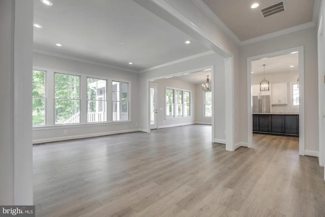 unfurnished living room featuring light wood finished floors, a notable chandelier, baseboards, and visible vents