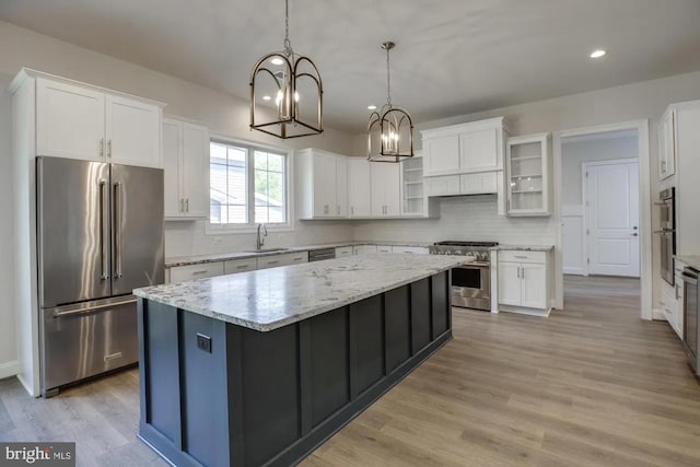 kitchen featuring a notable chandelier, a sink, premium appliances, a kitchen island, and white cabinets