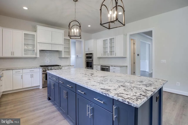 kitchen featuring an inviting chandelier, blue cabinets, a kitchen island, and stainless steel appliances