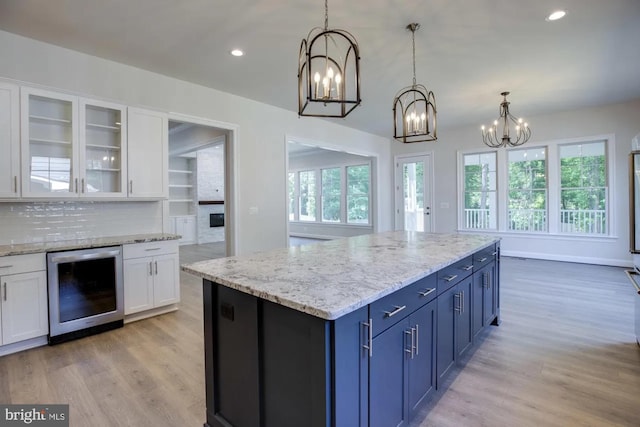 kitchen with light wood-style flooring, wine cooler, an inviting chandelier, and white cabinets