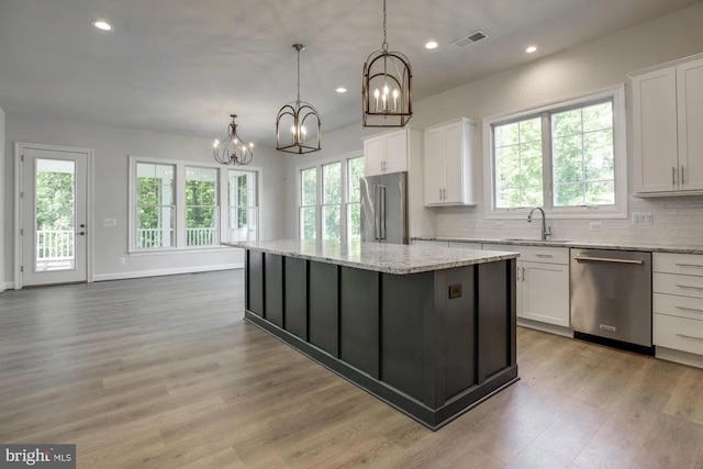 kitchen featuring visible vents, a kitchen island, a chandelier, stainless steel appliances, and a sink