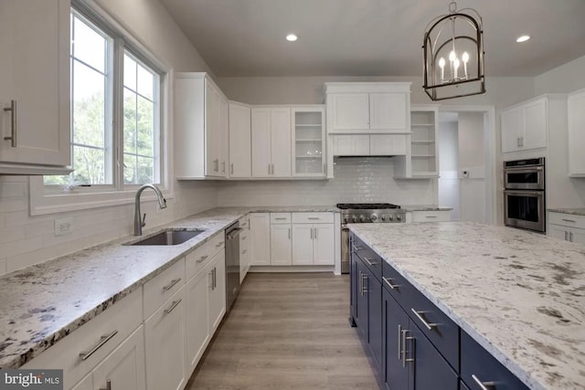 kitchen with blue cabinetry, white cabinetry, stainless steel appliances, and a sink