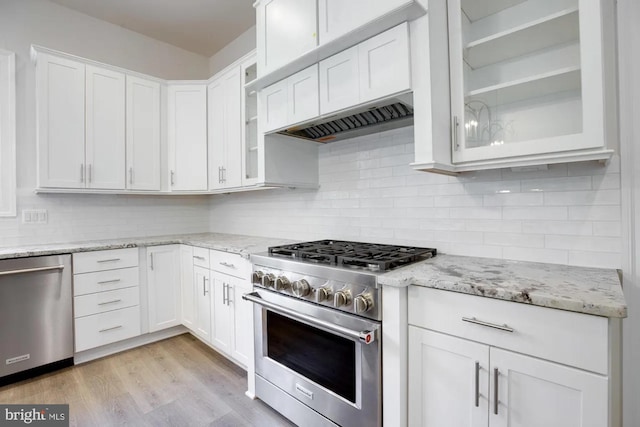 kitchen featuring light wood-type flooring, backsplash, appliances with stainless steel finishes, exhaust hood, and white cabinets