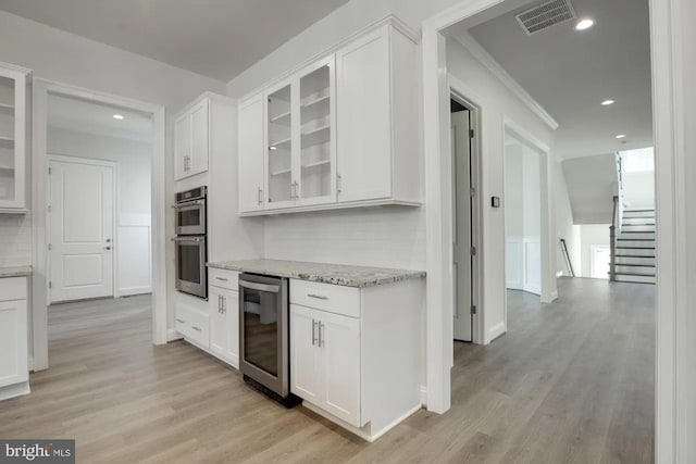 kitchen with visible vents, light stone countertops, wine cooler, double oven, and white cabinets