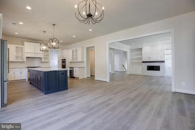 kitchen with open floor plan, white cabinetry, an inviting chandelier, light wood finished floors, and baseboards