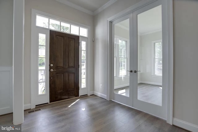 foyer with french doors, wood finished floors, and ornamental molding