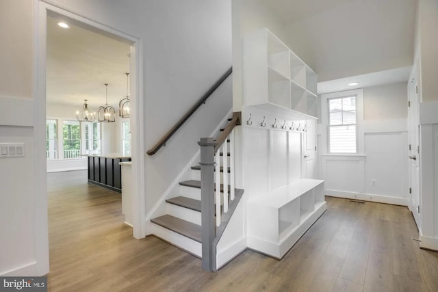 stairway with recessed lighting, a notable chandelier, and wood finished floors