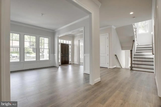 entryway with wood finished floors, stairway, a decorative wall, wainscoting, and crown molding