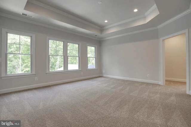 empty room featuring visible vents, a raised ceiling, and ornamental molding