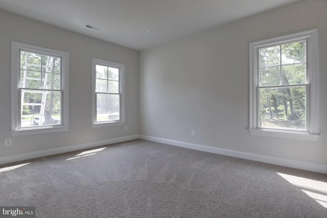 carpeted spare room with visible vents and baseboards