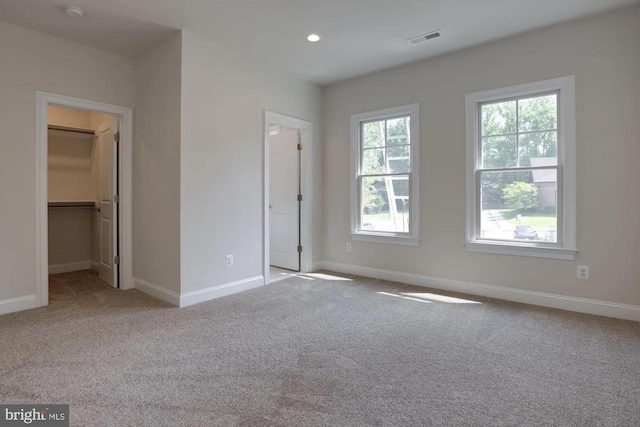 unfurnished bedroom with a spacious closet, visible vents, baseboards, carpet, and recessed lighting