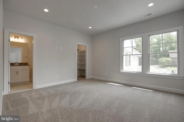 unfurnished bedroom with a spacious closet, recessed lighting, carpet, and visible vents