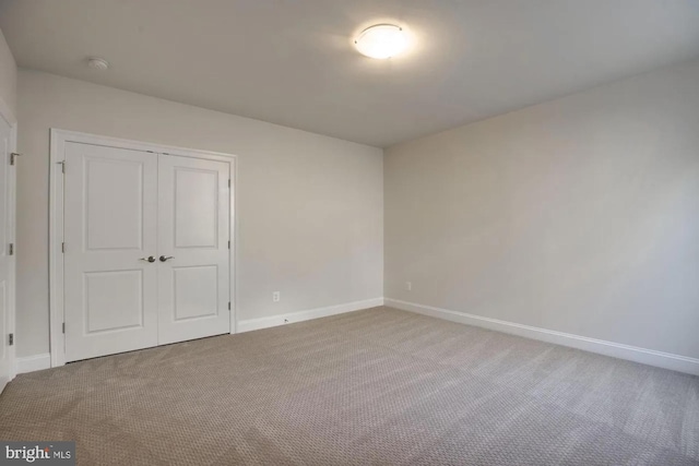 unfurnished bedroom featuring carpet, a closet, and baseboards