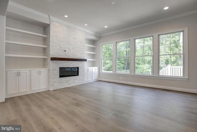 unfurnished living room featuring a fireplace, wood finished floors, a healthy amount of sunlight, and ornamental molding