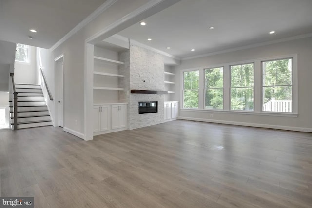 unfurnished living room featuring wood finished floors, a healthy amount of sunlight, and ornamental molding