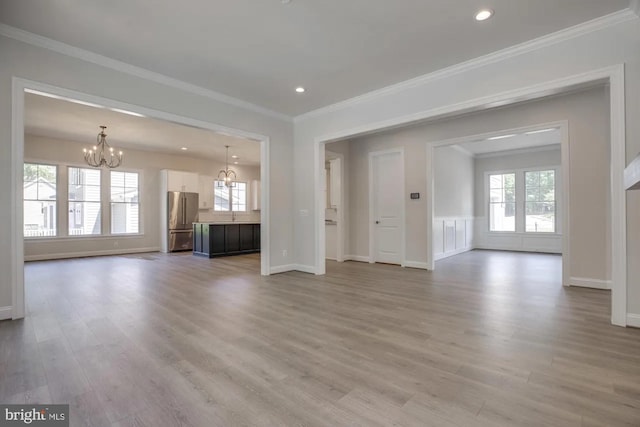 unfurnished living room featuring light wood-style floors, a wealth of natural light, and a chandelier