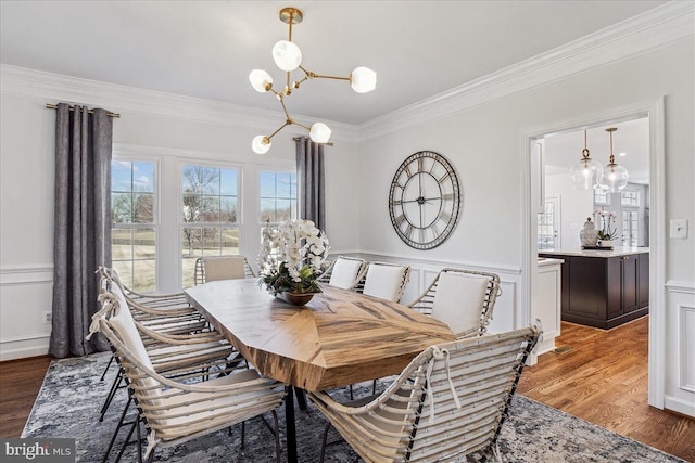 dining area featuring an inviting chandelier, a decorative wall, light wood finished floors, and ornamental molding