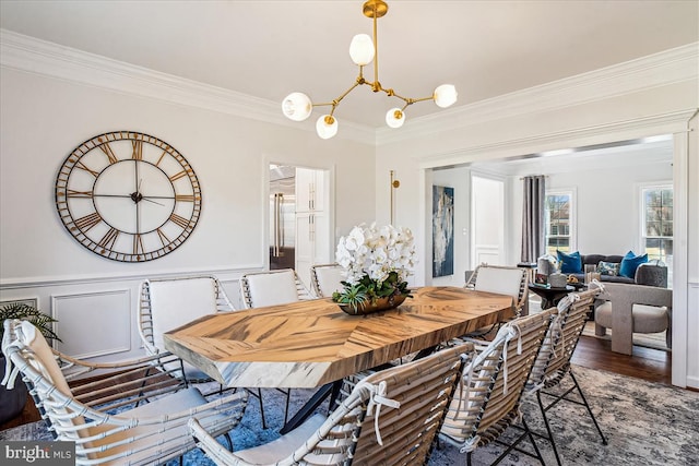 dining room with crown molding, a decorative wall, wood finished floors, and a wainscoted wall