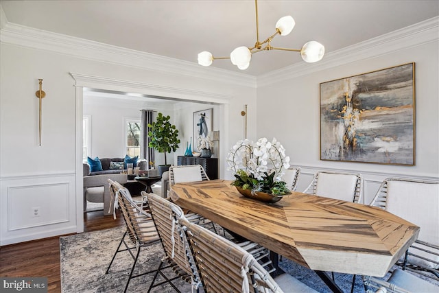 dining room featuring a decorative wall, crown molding, wainscoting, wood finished floors, and a notable chandelier