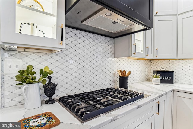 kitchen featuring decorative backsplash, exhaust hood, white cabinets, and stainless steel gas cooktop