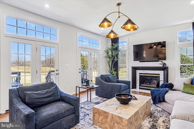 living room featuring a premium fireplace, recessed lighting, baseboards, and wood finished floors