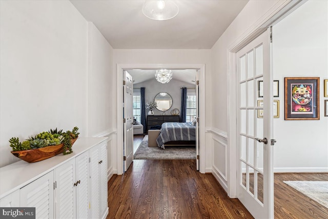 corridor with french doors, dark wood-type flooring, and lofted ceiling