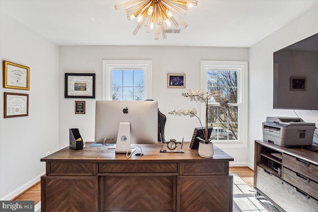 home office with a wealth of natural light, baseboards, an inviting chandelier, and light wood-style flooring