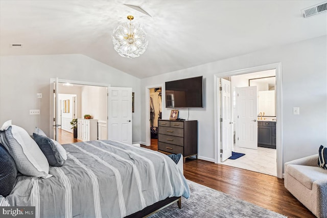 bedroom with wood finished floors, visible vents, an inviting chandelier, vaulted ceiling, and a spacious closet