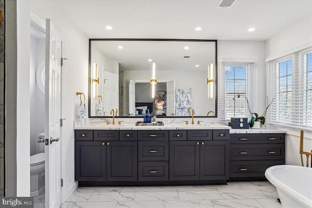 bathroom with double vanity, recessed lighting, a freestanding tub, marble finish floor, and a sink