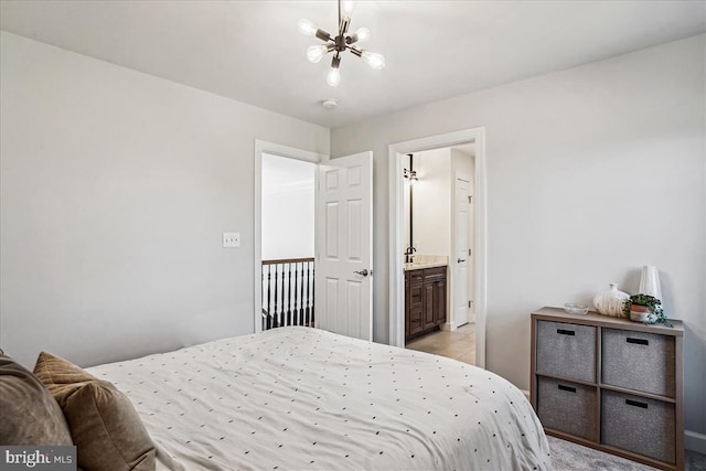 bedroom featuring ensuite bath, a notable chandelier, and a sink